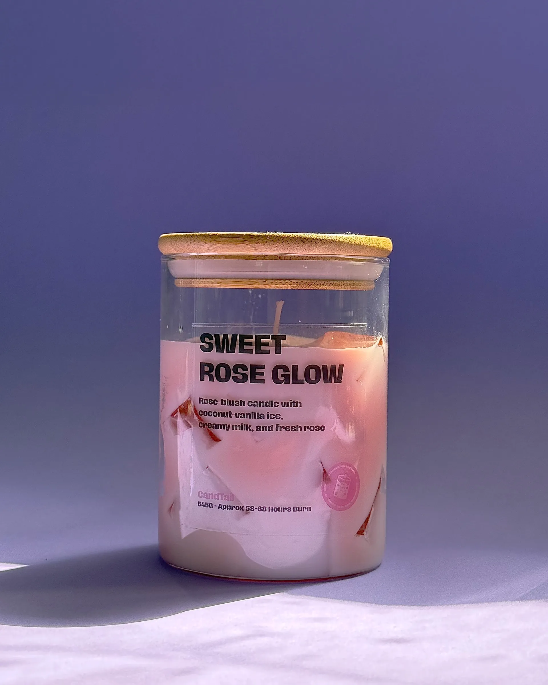 Sweet Rose Glow candle photographed against a purple backdrop