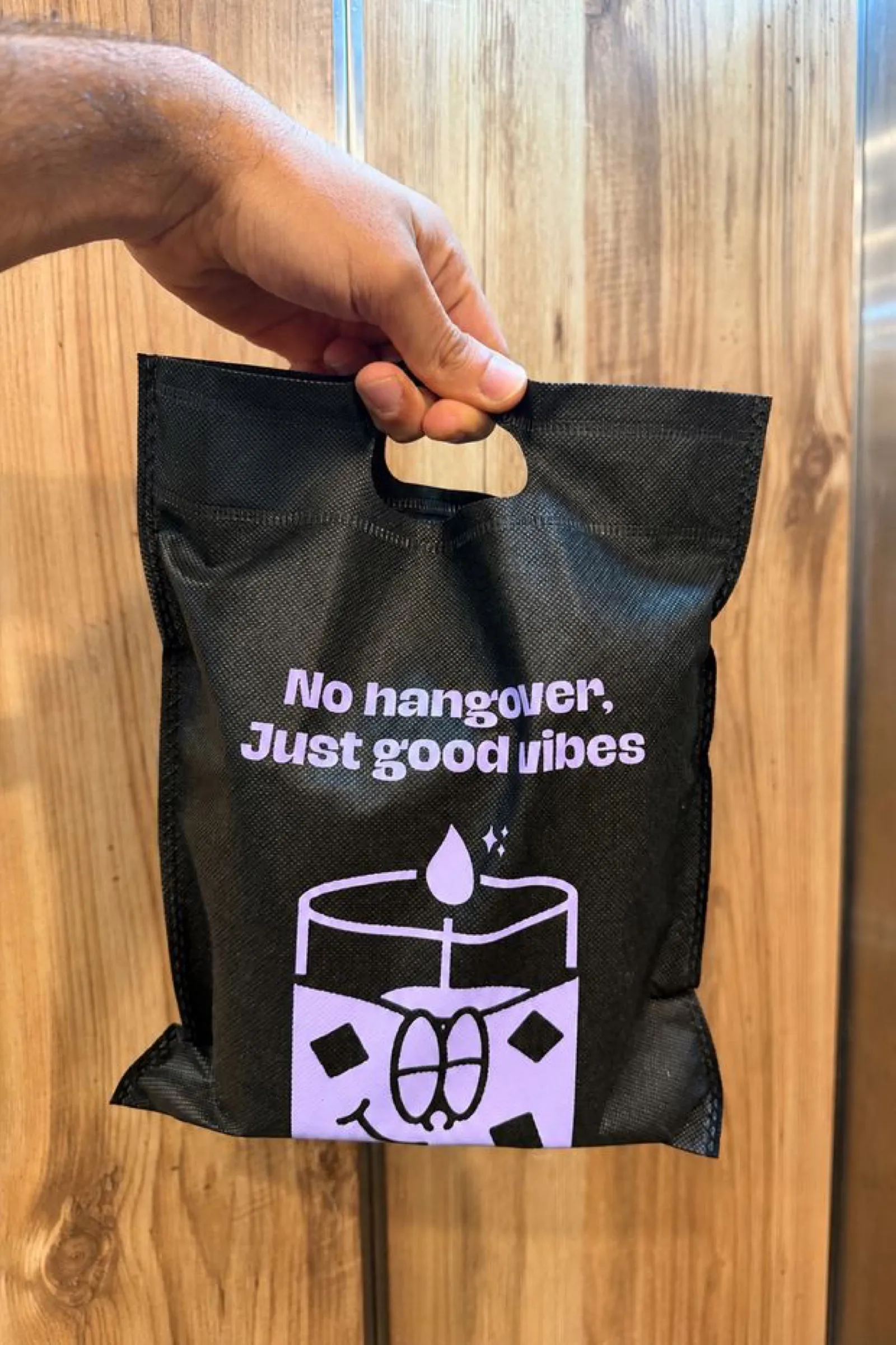 A Candtail order bag hanging on a wooden door